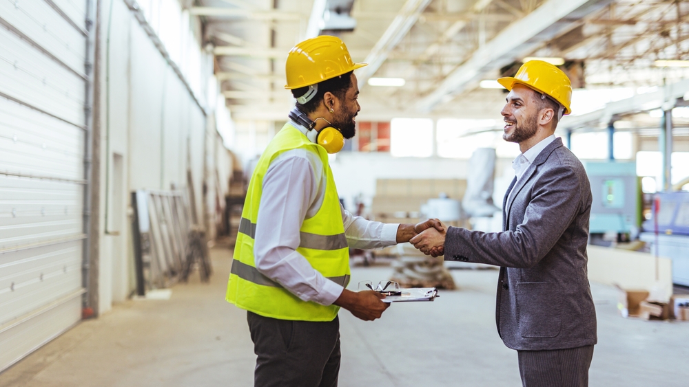 engineer,in,work,gear,and,a,businessman,shake,hands,in