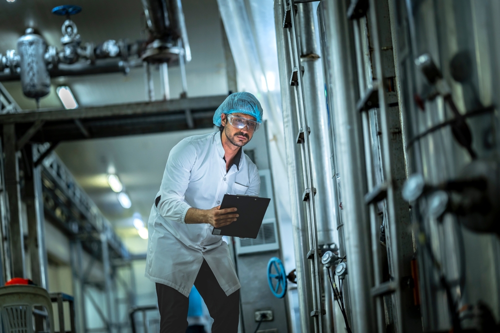 technician,examining,industrial,machinery,in,a,food,manufacturing,environment,emphasis
